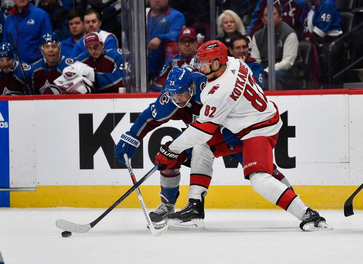 Colorado Avalanche left wing Miles Wood (28) and Carolina Hurricanes center Jesperi Kotkaniemi (82) battle for the puck in the first period at Ball Arena.