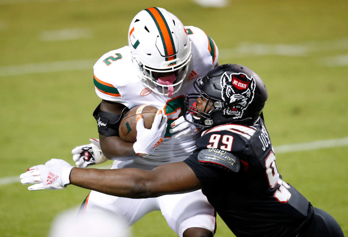 N.C. State defensive lineman Daniel Joseph (99) tackles Miami running back Donald Chaney Jr. (2) during the first half of N.C. State’s game against Miami at Carter-Finley Stadium in Raleigh, N.C., Friday, Nov. 6, 2020.