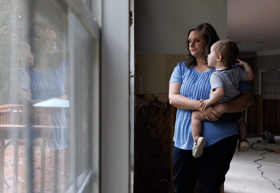 Rebecca Blough holds her 1-year-old son, Henry, in her Pittsboro home. The house was severely damaged by flooding from Tropical Storm Chantal.