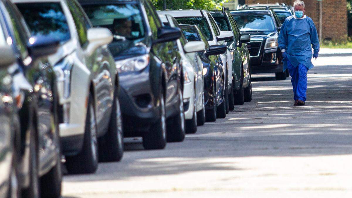 Torrey Hubred walks a line of cars waiting for coronavirus tests at a pop up testing site at Avery Street Recreation Center in Garner in July 2020.