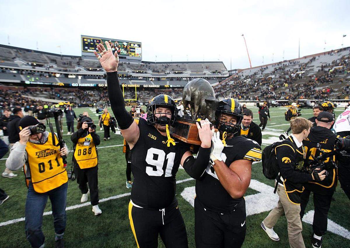 Defensive lineman Jonah Pace (91) and defensive lineman Bryce Hawthorne (96) of the Iowa Hawkeyes celebrate with the Floyd of Rosedale trophy after the match-up against the Minnesota Golden Gophers on Oct. 25, 2025 at Kinnick Stadium, in Iowa City, Iowa.