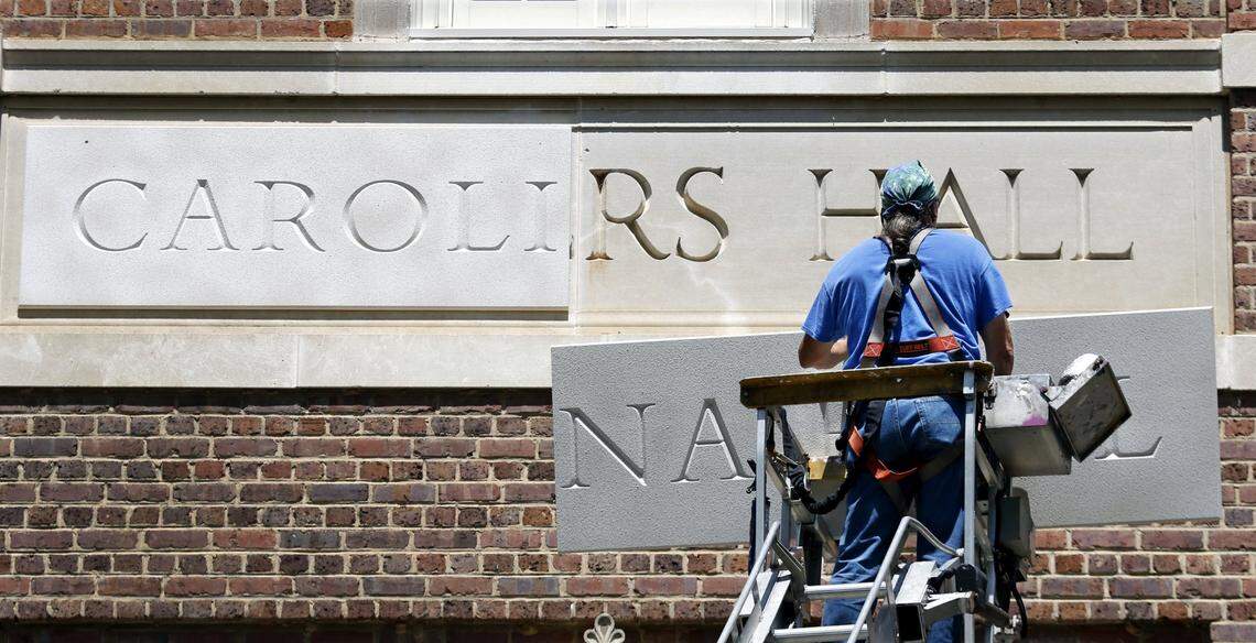 Sign installer Roger Phillips of Broach Custom Signs in Wendell, NC slowly rises with the second urethane panel of the new Carolina Hall nameplate Thursday afternoon, August 13, 2015 to cover the old Saunders Hall name on the UNC-CH campus. After an outcry over the personal history of the 19th century UNC alumnus William L. Saunders the university decided recently to change the name to Carolina Hall, removing all vestiges of the old name.
