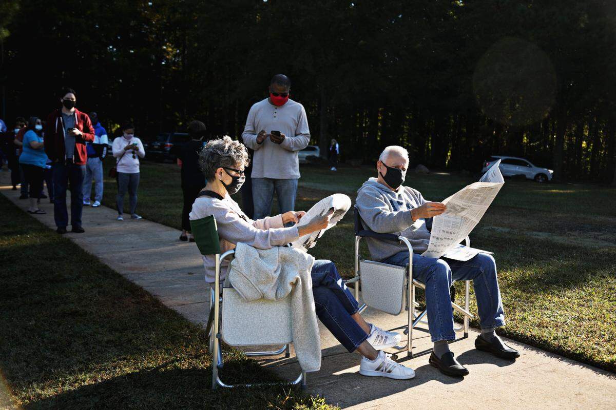 Barbara and Al Camacho pull out their lawn chairs and read the newspaper while waiting in line at Lake Lynn Community Center on Thursday morning, Oct. 15, 2020. “No matter how long it takes, I will wait all day,” says Al Camacho who was near the back of the very long line at at the Raleigh early voting site.