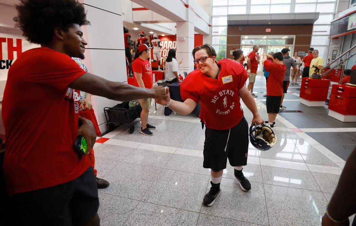 N.C. State wide receiver KC Concepcion greets Sam Hening during Victory Day at Carter-Finley Stadium in Raleigh, N.C., Friday, August 2, 2024. Victory Day is a partnership between the Wolfpack and GiGi’s Playhouse, a Down Syndrome achievement center in Raleigh. The event provided 52 cognitively and physically impaired people the chance to be football stars for the night.