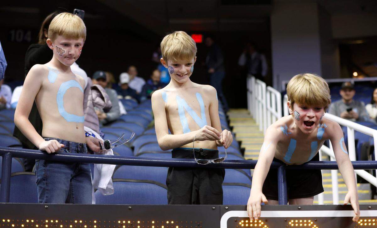 From left, William Lawrence, 9, Robert Quick, 8, and George Schultz, 9, all of Winston-Salem cheer on the Tar Heels as they take the court to warmup before UNC’s game against Boston College in the second round of the New York Life ACC Men’s Basketball Tournament in Greensboro, N.C., Wednesday, March 8, 2023.