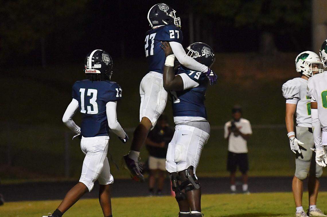 Southeast Raleigh's 	Grayson Williams (79) hoists up running back James Adams IV (27) after his touchdown against Cardinal Gibbons in the second half. The Southeast Raleigh Bulldogs and the Cardinal Gibbons Crusaders met in a non-conference football game in Raleigh, N.C. September 12, 2025