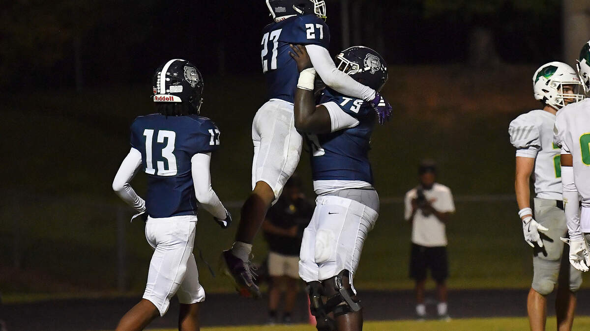 Southeast Raleigh's Grayson Williams (79) hoists up running back James Adams IV (27) after his touchdown against Cardinal Gibbons in the second half. The Southeast Raleigh Bulldogs and the Cardinal Gibbons Crusaders met in a non-conference football game in Raleigh, N.C. September 12, 2025