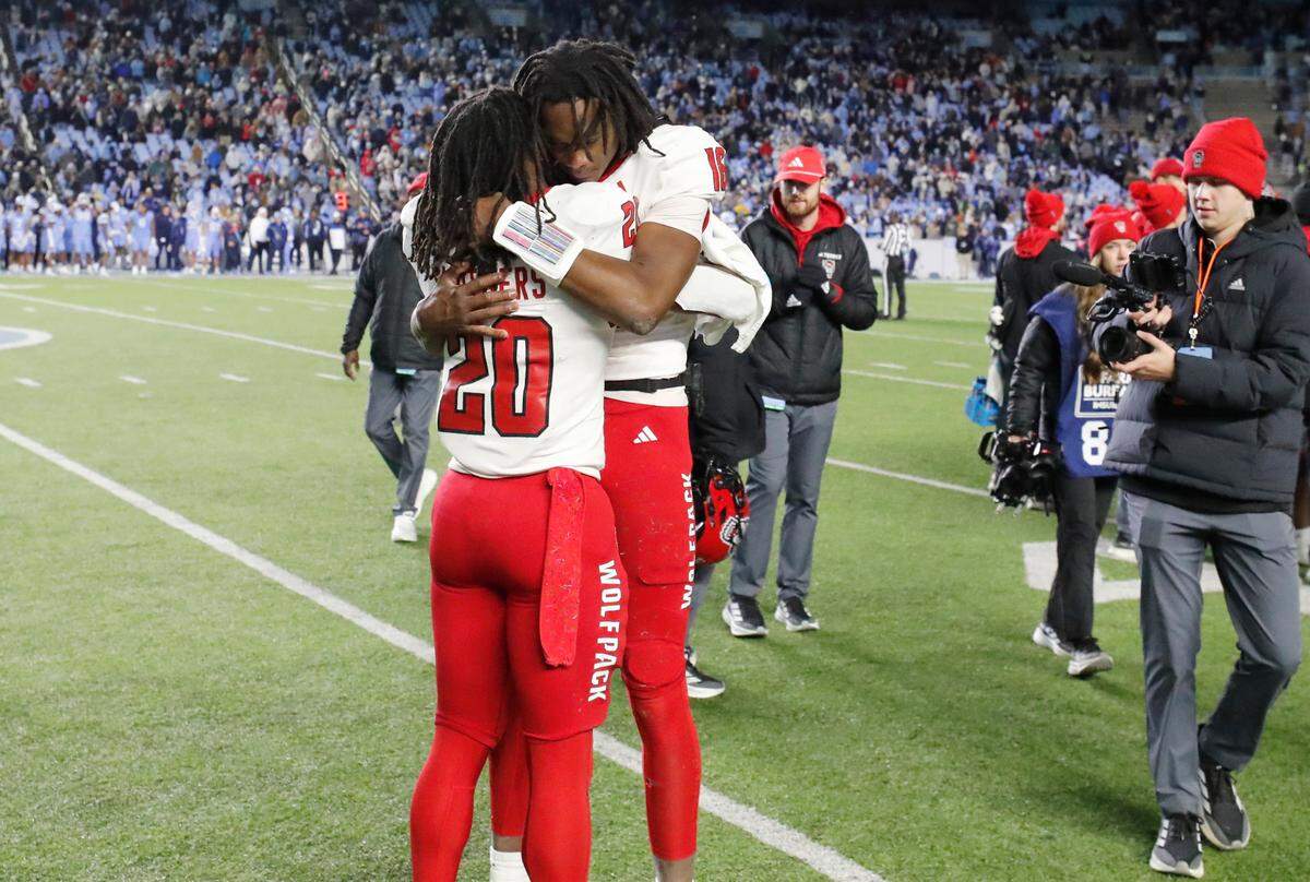 N.C. State quarterback CJ Bailey (16) hugs running back Hollywood Smothers (20) in the final moments of the Wolfpack’s 35-30 victory over UNC at Kenan Stadium in Chapel Hill, N.C., Saturday, Nov. 30, 2024.