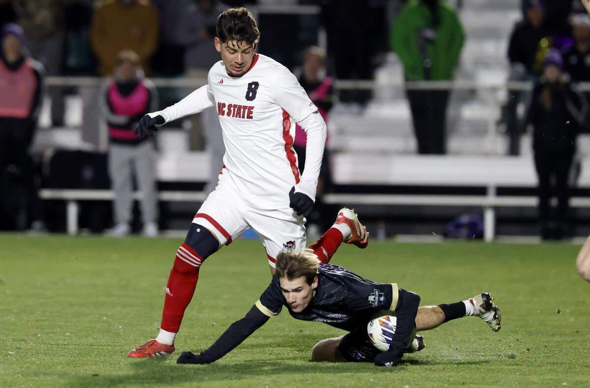 Washington's Richie Aman (10) goes down in front of N.C. State's Justin McLean (8) during the first half of N.C. State’s game against Washington in the 2025 Men’s Soccer National Championship at WakeMed Soccer Park in Cary, N.C., Monday, Dec. 15, 2025. No hand ball was called.