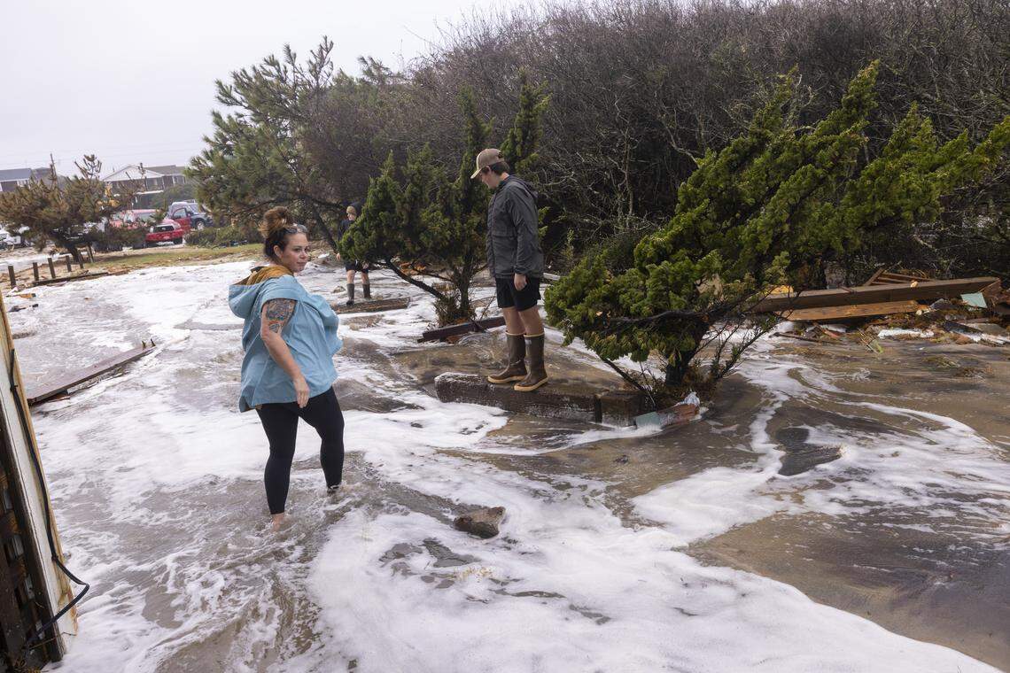 Onlookers watch as overwash from rough surf swamps part of the coastline near beach homes during high tide on Sunday, Oct. 12, 2025, in Buxton during a nor’easter. Nine homes in the community have collapsed into the Atlantic Ocean since mid-September.