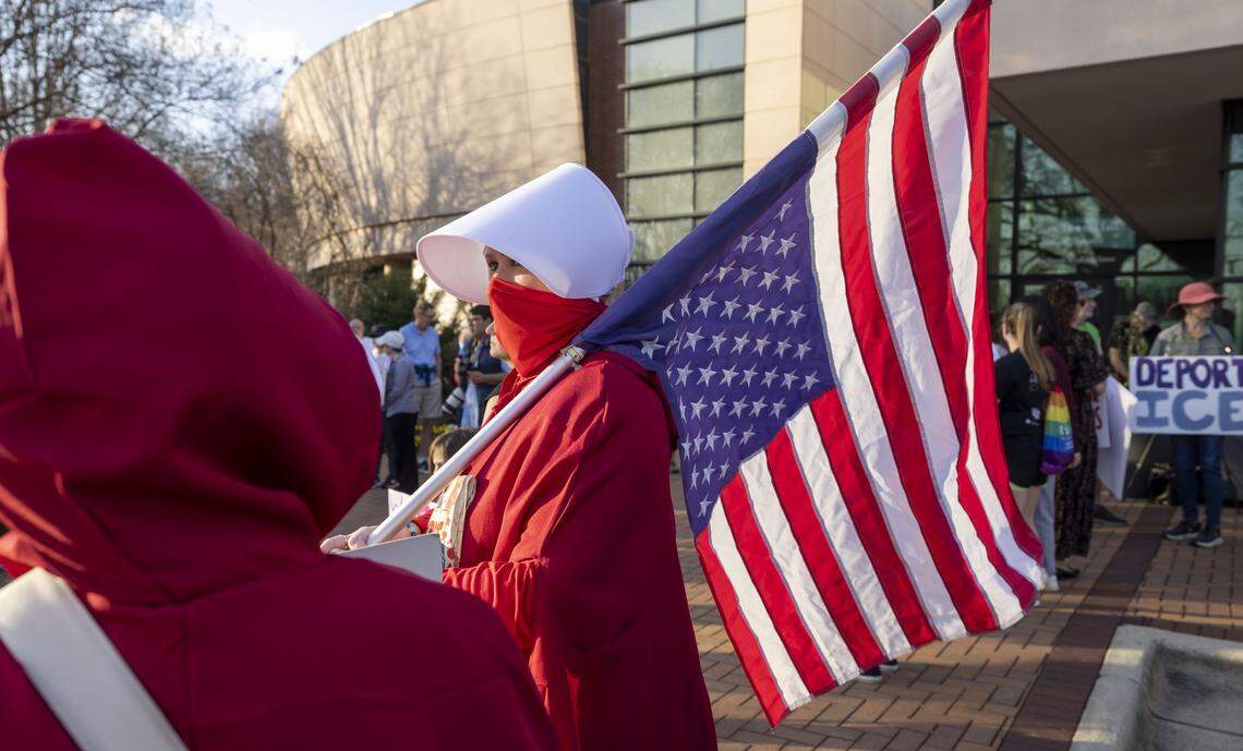 Karen Salley of Cary, dressed in a red cloak and white bonnet, participates in an anti-ICE demonstration on Thursday, March 5, 2026 at Town Hall in Cary, N.C.