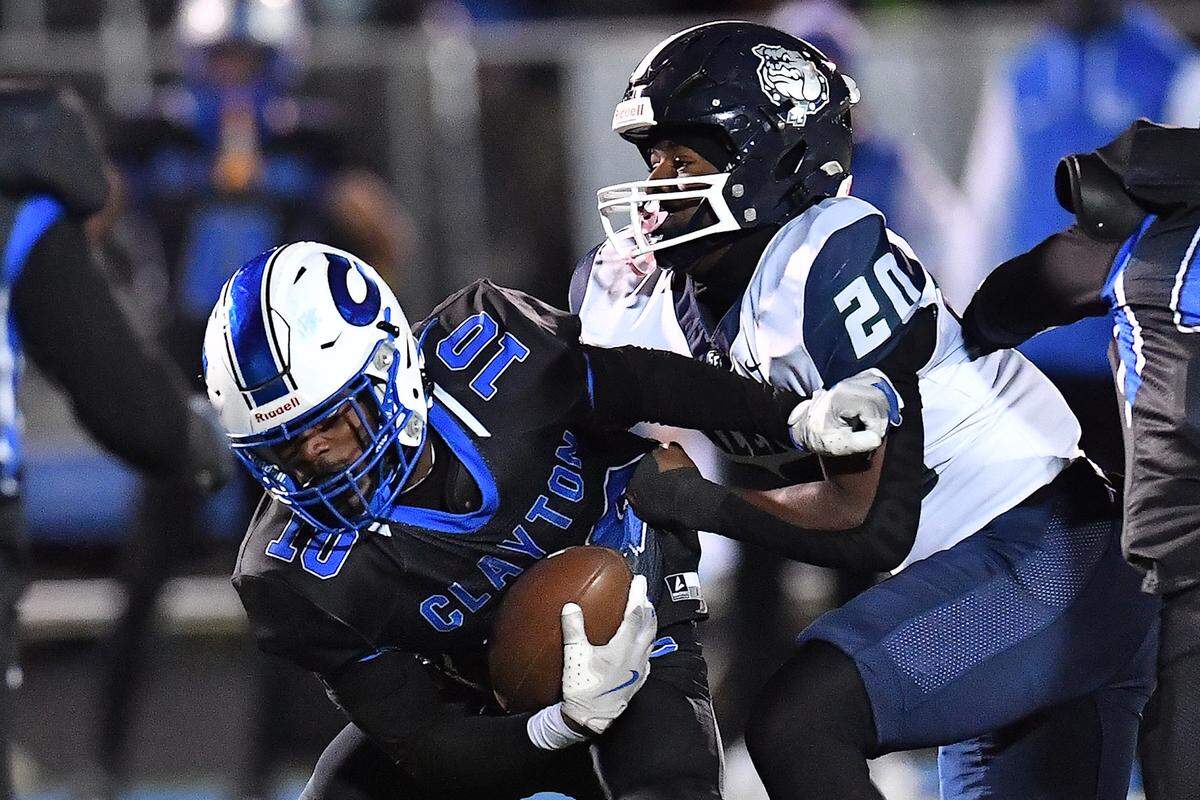 Southeast Raleigh linebacker Josiah Heath (20) grapples Clayton strong safety Charles Smith (10) during the first half. The Clayton Comets and the Southeast Raleigh Bulldogs met in the fourth round of the NCHSAA 7A Playoffs in Clayton, N.C. on November 28, 2025.