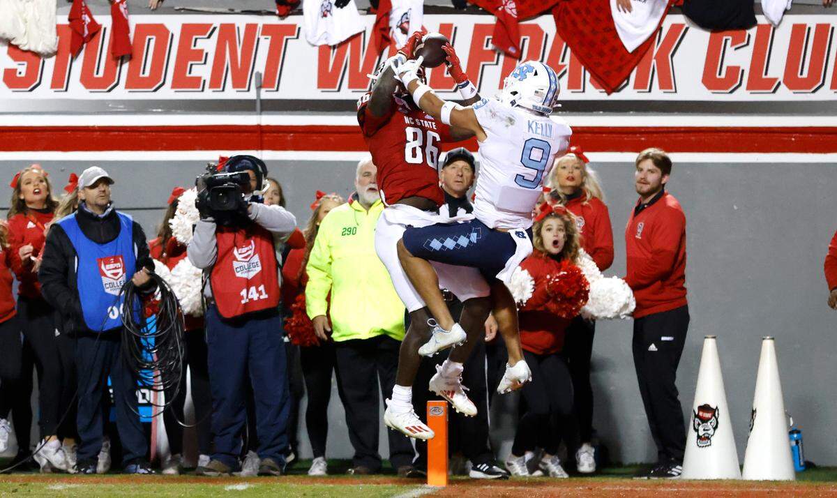 N.C. State wide receiver Emeka Emezie (86) makes what would be the game winning touchdown reception as North Carolina defensive back Cam’Ron Kelly (9) defends late in the second half of N.C. State’s 34-30 victory over UNC at Carter-Finley Stadium in Raleigh, N.C., Friday, November 26, 2021.