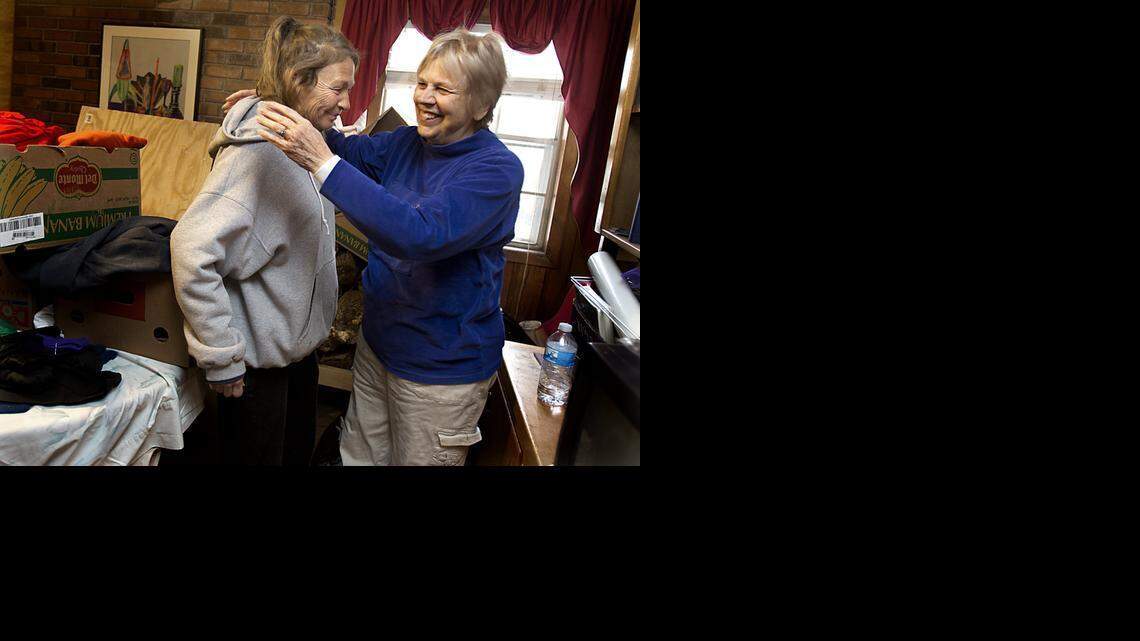 Surrounded by winter clothing donations in her basement, Alice McGee of Garner, right, embraces one of her homeless clients, Eileen Leighly, 55, after inviting her to her home to dry her clothing and blankets on Tuesday. 
