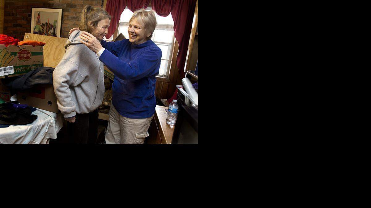 Surrounded by winter clothing donations in her basement, Alice McGee of Garner, right, embraces one of her homeless clients, Eileen Leighly, 55, after inviting her to her home to dry her clothing and blankets on Tuesday. 
