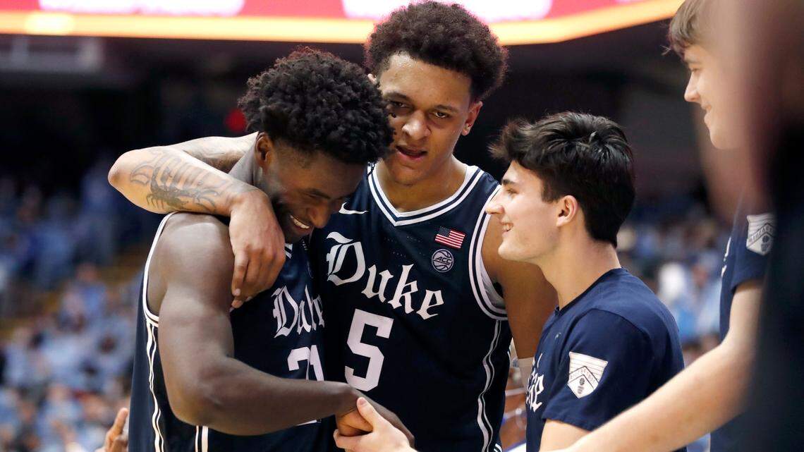 Duke’s A.J. Griffin (21) smiles with Paolo Banchero (5) and Michael Savarino (30) as he comes back to the bench late in the second half of Duke’s 87-67 victory over UNC at the Smith Center in Chapel Hill, N.C., Saturday, Feb. 5, 2022.