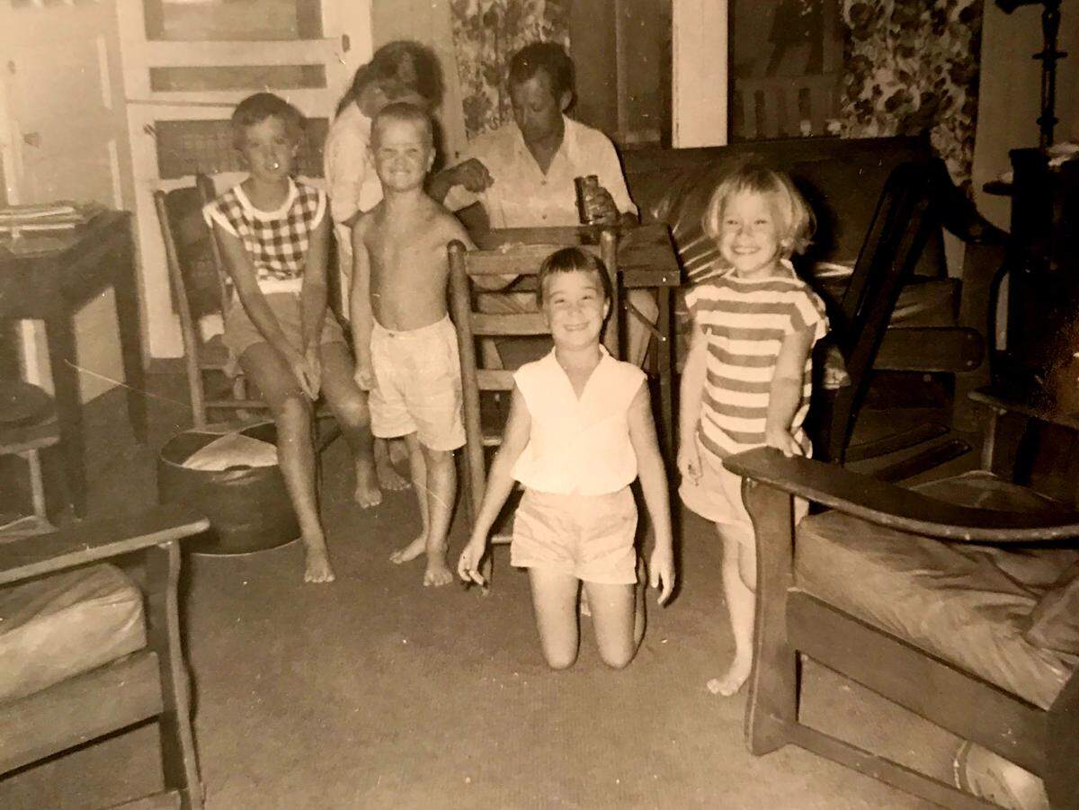 Beth Burns and her cousins gather around a card table during a family vacation in the 1950s. Burns is in the striped shirt on the right side of the photo, next to her father. 
