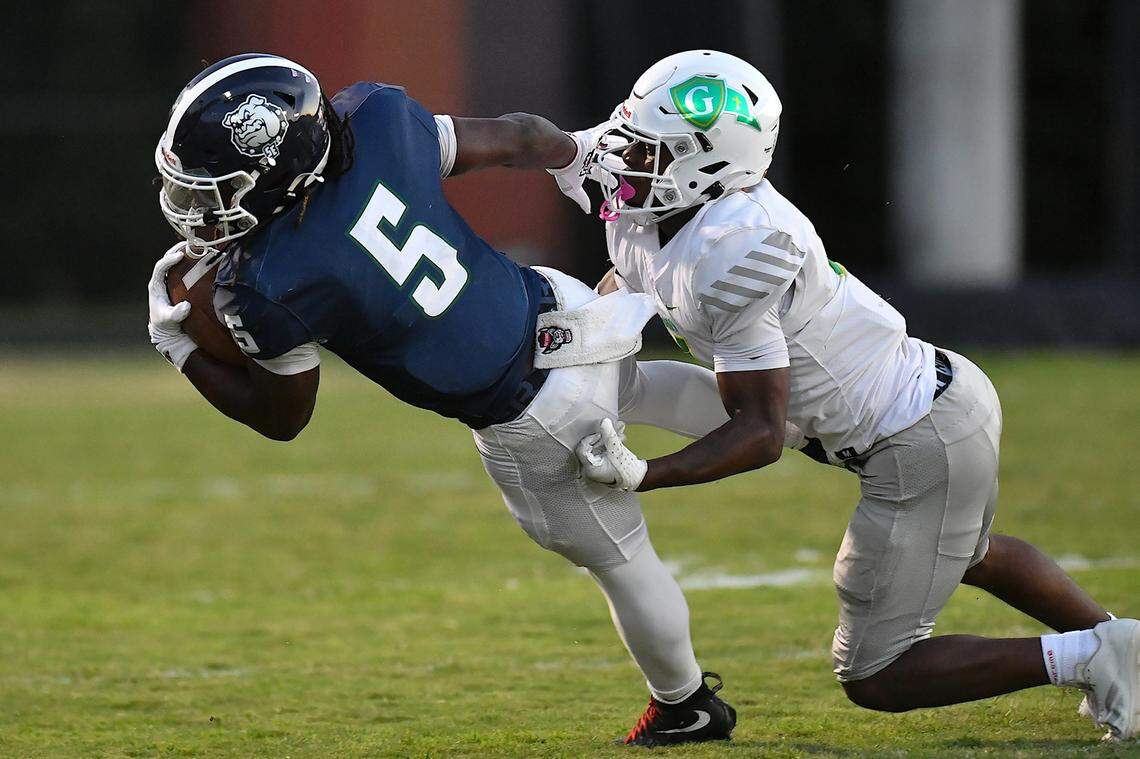 Southeast Raleigh running back Christian Freeman (5) is tackled by Cardinal Gibbons defensive back Braylon Peebles (4) during the first half. The Southeast Raleigh Bulldogs and the Cardinal Gibbons Crusaders met in a non-conference football game in Raleigh, N.C. September 12, 2025
