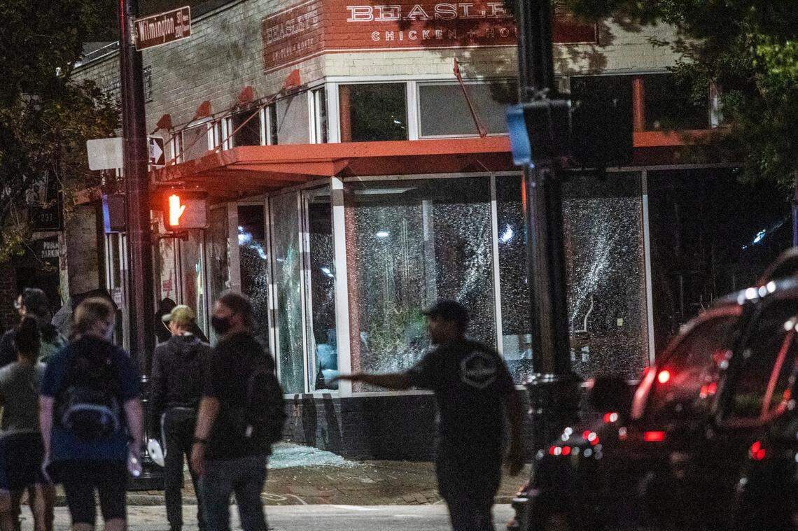 Protesters march past smashed windows at BeasleyÕs Chicken + Honey restaurant in downtown Raleigh Saturday Sept. 26, 2020. Demonstrators protested the decision by a Kentucky grand jury to clear three Louisville police officers of criminal wrongdoing in the shooting death of Breonna Taylor.