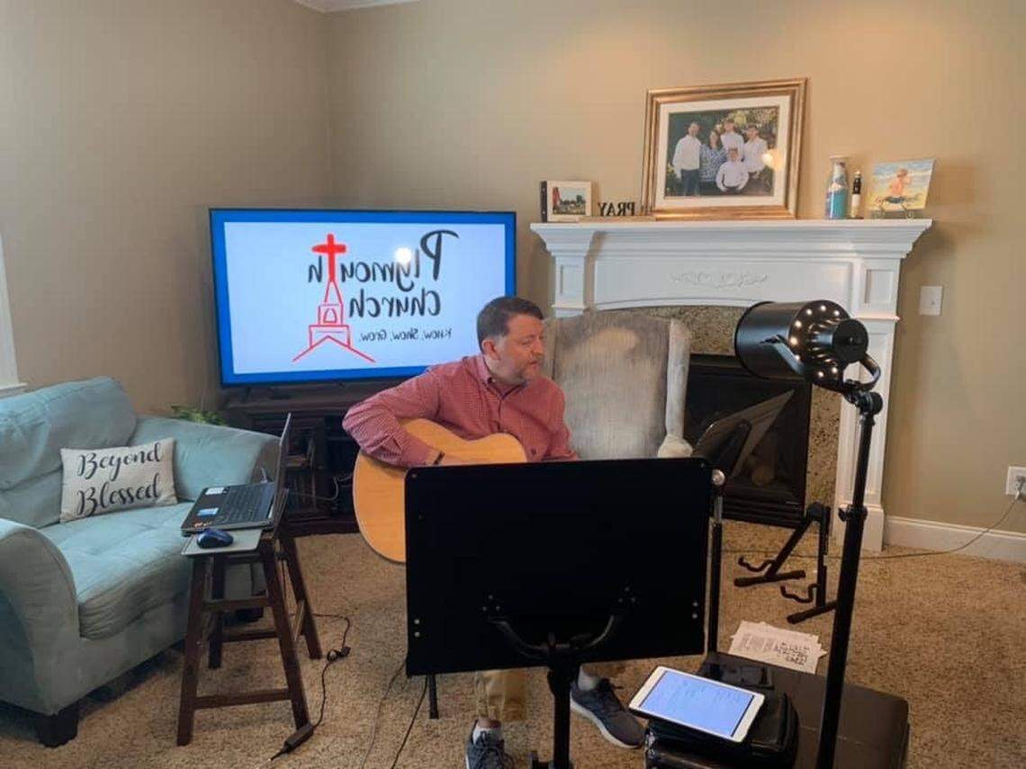 Chris Parton, pastor of Plymouth Church in Wake County, plays guitar and sings during a Sunday morning worship service. Like other congregations, Plymouth is unable to meet in the sanctuary during the COVID-19 pandemic.