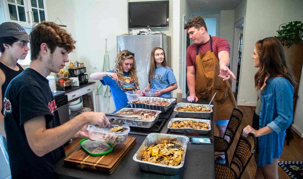 Tom and Rachael Sullivan, at right, share food with college students Tuesday, July 6, 2021 at their home in Raleigh. The Sullivans started offering free food for college students after they went viral on Tiktok and, what started out as Tom’s secret Instagram account to keep track of Rachael’s favorite meals, @mealssheeats, gained more than thousands of followers.