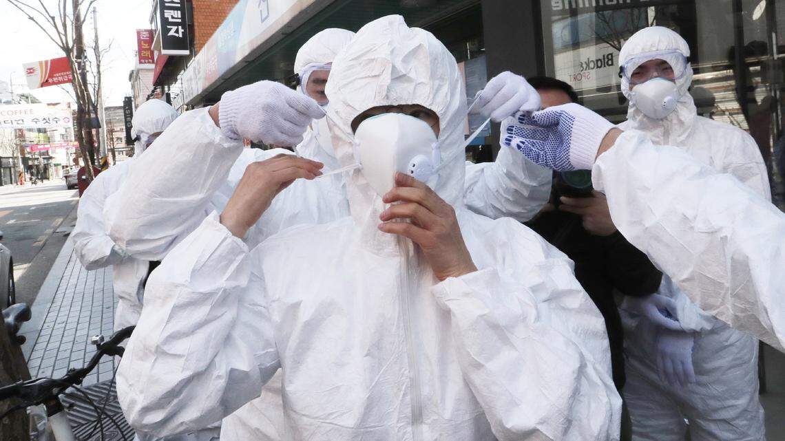 A worker wears a face mask to spray disinfectant as a precaution against the coronavirus at a shopping street in Seoul, South Korea, Thursday, Feb. 27, 2020. South Korea and China each reported hundreds more virus cases Thursday as the new illness persists in the worst-hit areas and spreads beyond borders.