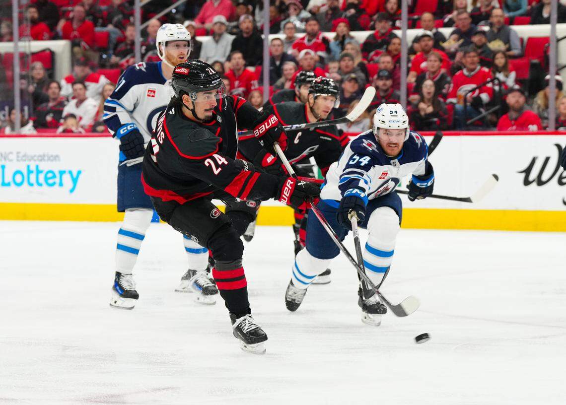 Carolina Hurricanes center Seth Jarvis (24) gets the shot away against Winnipeg Jets defenseman Dylan Samberg (54) during the first period at Lenovo Center.