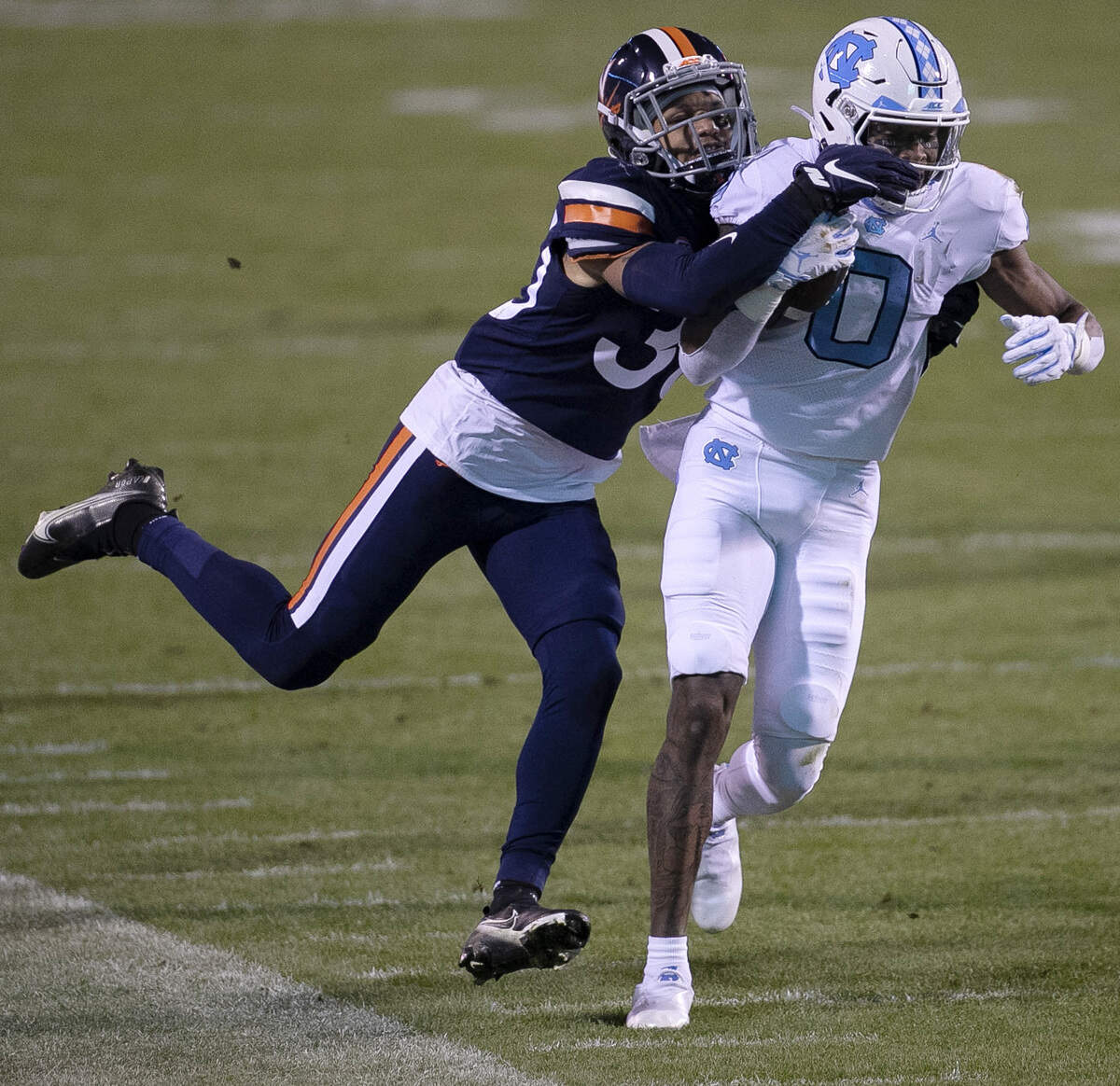 Virginia’s D’Angelo Amos (30) stops North Carolina’s Emery Simmons (0) after a 22-yard pass reception from quarterback Sam Howell (7) in the second quarter on Saturday, October 31, 2020 at Scott Stadium in Charlottesville, Va.