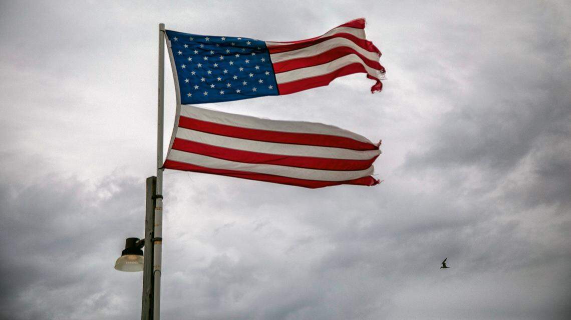 A seagull flies near a shredded American flag at the end of the Ocean Crest Pier on Oak Island Monday, Aug. 3, 2020 as Tropical Storm Isaias moves towards the southeast coast. The storm is expected to strengthen to a hurricane before making landfall.