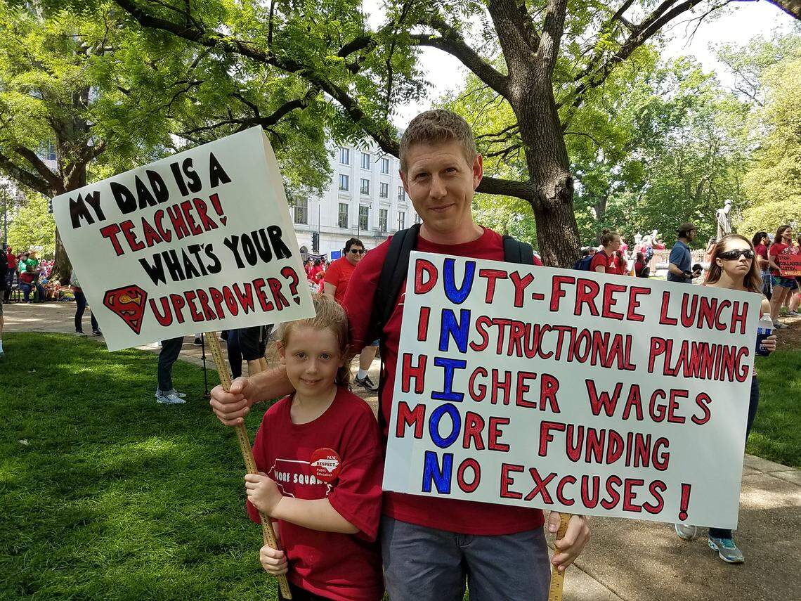 Frank Burns, a math teacher at Moore Square Middle School, with his daughter, Madeline, a first-grader at Willow Springs Elementary. Thousands of teachers carried signs May 1, 2019, in downtown Raleigh during the May 1 “Day of Action” organized by the N.C. Association of Educators. The signs ranged from clever pop culture references to more direct demands for higher pay, supplies and respect.