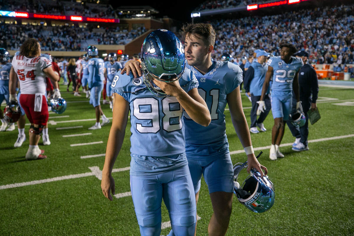 North Carolina punter Ben Kiernan (91) consoles kicker Noah Burnette (98) after Burnette missed a 35-yard field goal attempt in overtime to give N.C. State a 30-27 victory on Friday, November 25, 2022 at Kenan Stadium in Chapel Hill, N.C.