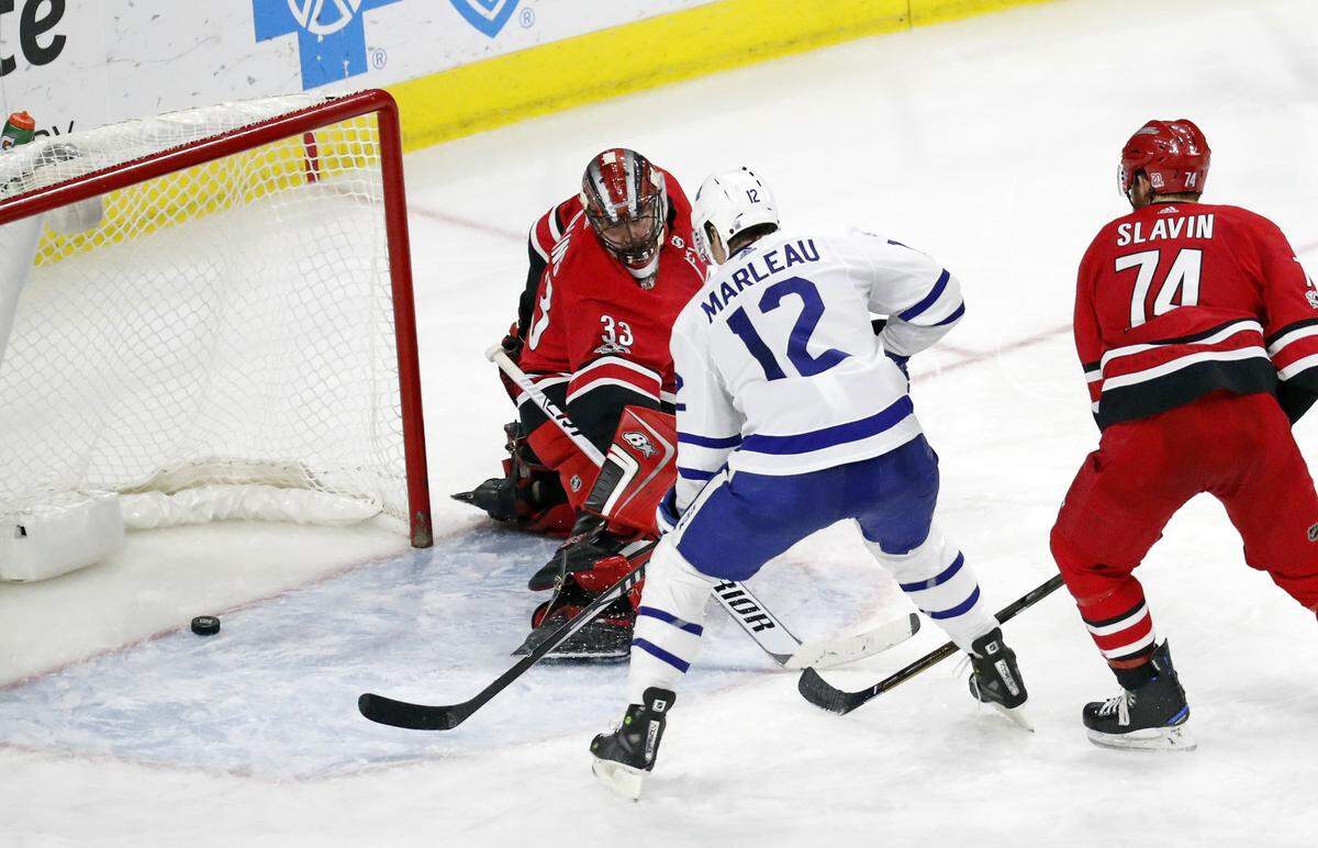The Leafs' Patrick Marleau (12) puts the puck past the Canes' Scott Darling (33) and Jaccob Slavin (74) for what proved to be the game winning goal during the third period of an NHL game played between the Carolina Hurricanes and the Toronto Maple Leafs at PNC Arena in Raleigh, N.C. on  Nov. 24, 2017.  The Leafs beat the Canes 5-4.