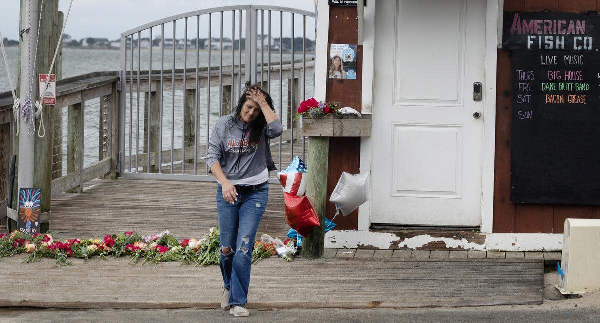 A woman walks away after placing balloons at a memorial for victims of a shooting at the American Fish Company in Southport, N.C., Sunday afternoon, Sept. 28, 2025.  A man in a boat shot into the popular nightspot along the water Saturday night, killing three people.  