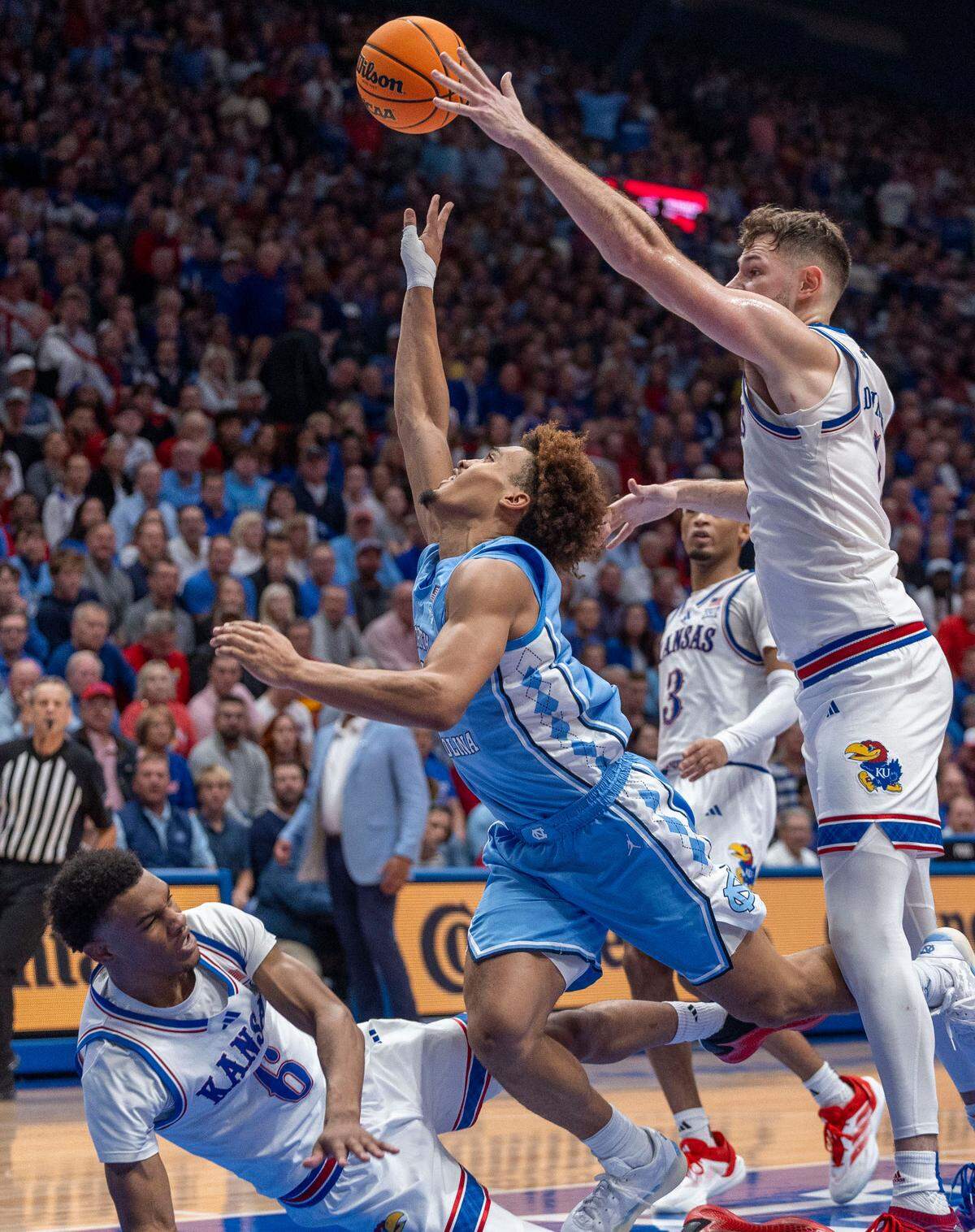 North Carolina guard Seth Trimble (7) drives to the basket between Kansas center Hunter Dickinson (1) and guard Rylan Griffen (6) in the second half on Friday, November 8, 2024 at Allen Fieldhouse in Lawrence, Kansas. Trimble lead North Carolina with 19 points.