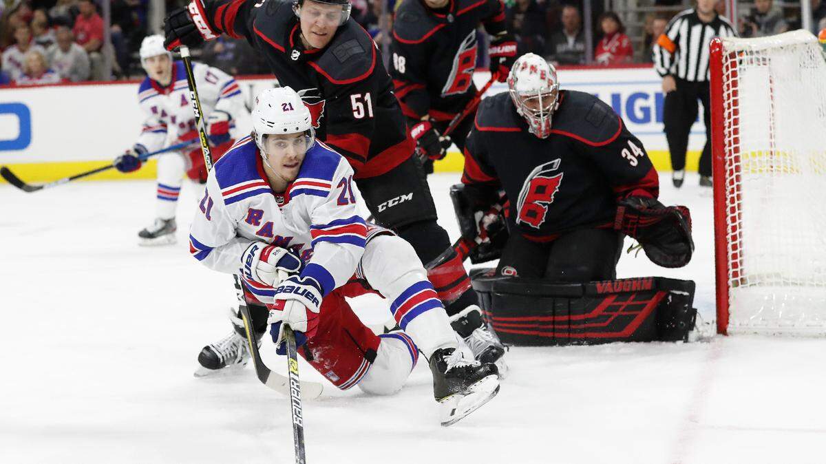 New York Rangers center Brett Howden (21) falls while passing the puck as Carolina Hurricanes goaltender Petr Mrazek (34) and defenseman Jake Gardiner (51) defend during the third period of an NHL hockey game in Raleigh, N.C., Friday, Feb. 21, 2020. (AP Photo/Gerry Broome)