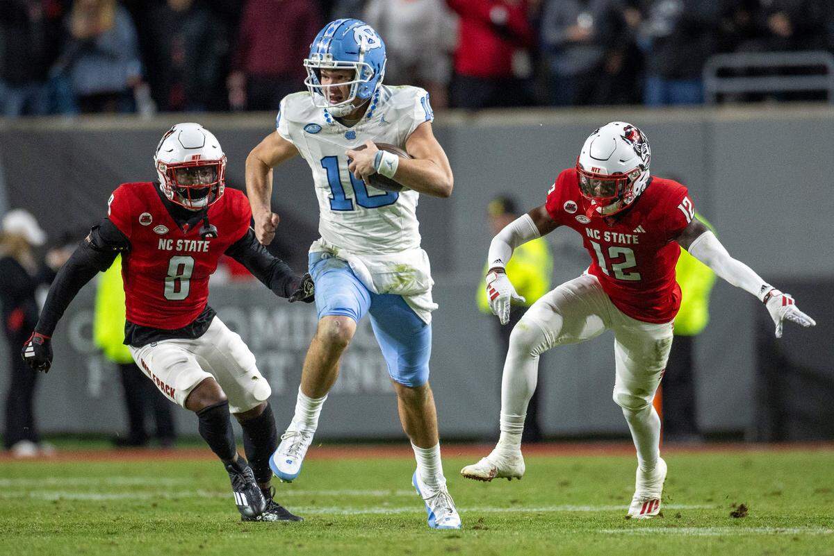 North Carolina quarterback Drake Maye (10) breaks open on a 56-yard gain ahead of N.C. State’sRobert Kennedy (8) and Devan Boykin (12) in the third quarter against N.C. State on Saturday, November 25, 2023 at Carter-Finley Stadium in Raleigh, N.C.