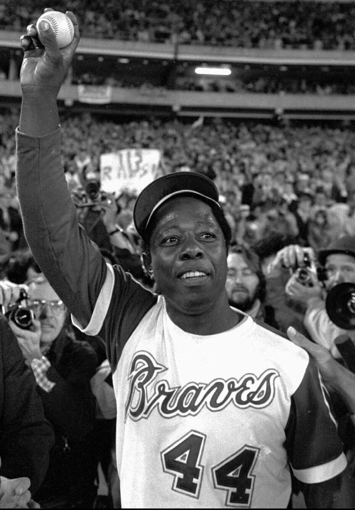 In this April 8, 1974, file photo, Atlanta Braves’ Hank Aaron holds aloft the ball he hit for his 715th career home in Atlanta. Hank Aaron, who endured racist threats with stoic dignity during his pursuit of Babe Ruth but went on to break the career home run record in the pre-steroids era, died early Friday, Jan. 22, 2021. He was 86. The Atlanta Braves said Aaron died peacefully in his sleep. No cause of death was given.