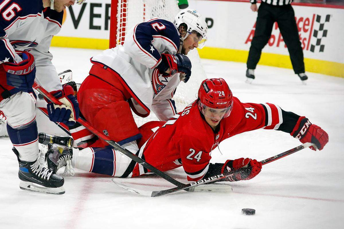 Carolina Hurricanes’ Seth Jarvis (24) tries to control the puck after colliding with Columbus Blue Jackets’ Andrew Peeke (2) during the second period of an NHL hockey game in Raleigh, N.C., Thursday, Jan. 13, 2022. (AP Photo/Karl B DeBlaker)