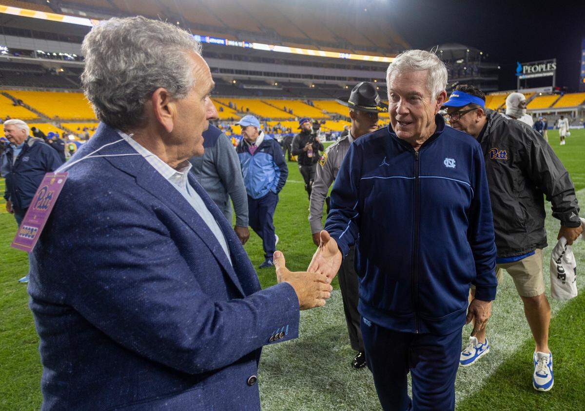 North Carolina athletic director Bubba Cunningham congratulates coach Mack Brown following the Tar Heels’ 41-24 victory over Pitt on Saturday, September 23, 2023 at Acrisure Stadium in Pittsburgh, Pa.