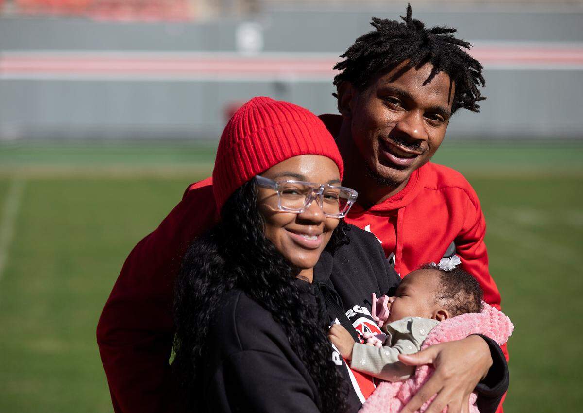 N.C. State’s Rakeim Ashford and Asia Owens stand with their three-month-old daughter, Ra’Kiya, on the field at Carter-Finley Stadium on Tuesday, Nov. 14, 2023, in Raleigh, N.C.