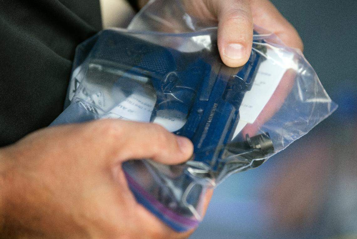 At deputy holds a pistol turned in at a buy-back event held by the Durham Sheriff’s Dept., Saturday, Aug. 6, 2022.