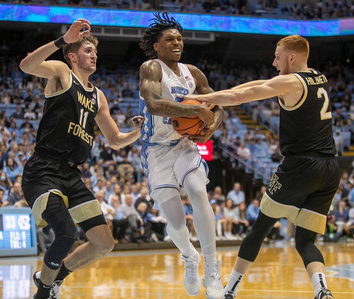 Wake Forest’s Cameron Hildreth (2) and Andrew Carr (11) trap North Carolina’s Caleb Love (2) during the first half on Wednesday, January 4, 2023 at the Smith Center in Chapel Hill, N.C.