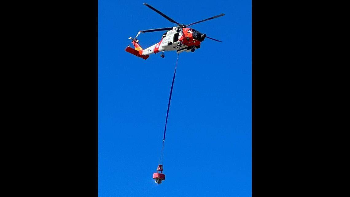 A U.S. Coast Guard helicopter out of Elizabeth City carries a large red buoy away from the beach at Cape L.ookout National Seashore.