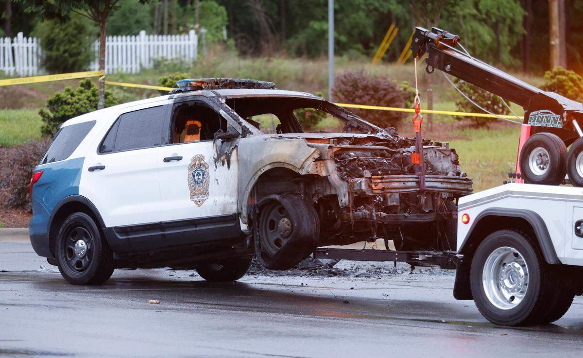 A burned out police vehicle is ready to be towed outside the police station in Southeast Raleigh Saturday, May 7, 2022. Raleigh police said a man died earlier Saturday after four police officers shot him outside the station. Police officers shot him after they saw him throwing “multiple” Molotov cocktails at vehicles in a parking lot near the police station, Chief Estella Patterson said at a news conference Saturday night. He then threw the “incendiary weapons” toward officers, and one came within close proximity of an officer, Patterson said.