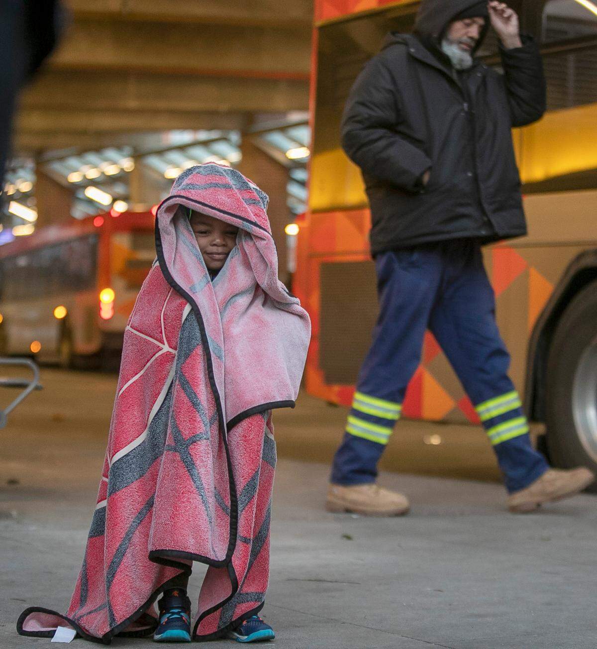 Three-year-old Amorhi Allen keeps warm wrapped in his Spiderman blanket as he waits for for a bus ride home with his father at the GoRaleigh Station downtown on Friday, December 23, 2022 in Raleigh, N.C. Arctic cold, coupled with strong winds, dropped temperatures into the 20’s on Friday afternoon.