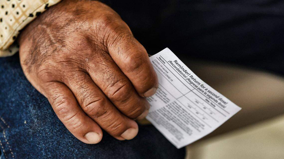 A man holds his COVID vaccination card while waiting to get his shot at at an event by the Episcopal Farmworker Ministry targeting members of the Hispanic community in August 2021.