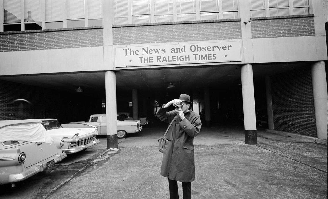 A News & Observer and Raleigh Times photographer is seen with his Leica rangefinder camera in the rear parking lot of the old offices at 215 S. McDowell Street in Downtown Raleigh in 1961.