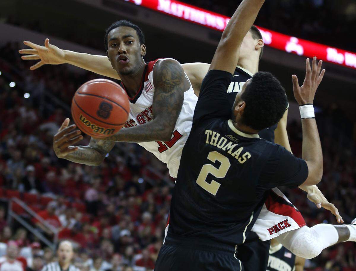 N.C. State’s Cat Barber (12) passes around Wake Forest’s Devin Thomas (2) and Konstantinos Mitoglou (44) during the second half of N.C. State’s 78-65 victory over Wake Forest at PNC Arena in Raleigh, N.C., Saturday, Dec. 6, 2014.