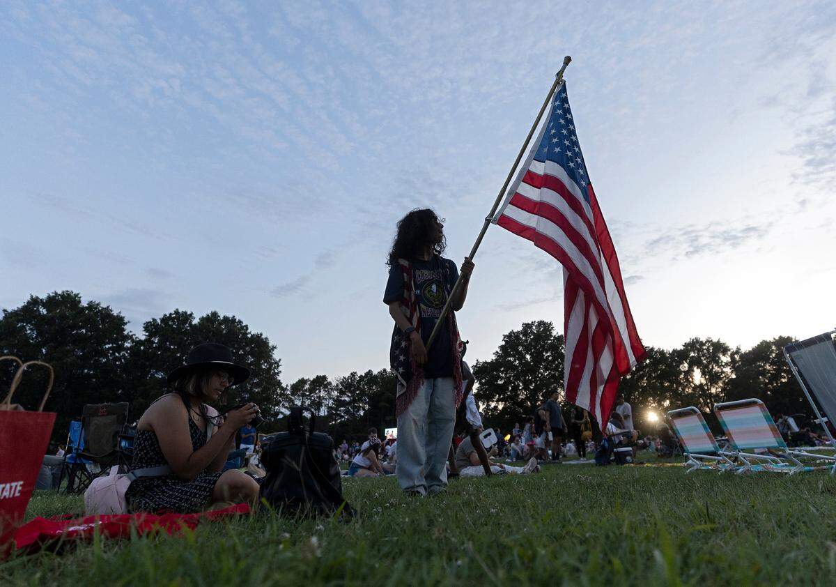 Ricardo Gomez-Alejo holds an American flag during an Independence Day celebration at Dorothea Dix Park on Tuesday, July 4, 2023, in Raleigh, N.C.