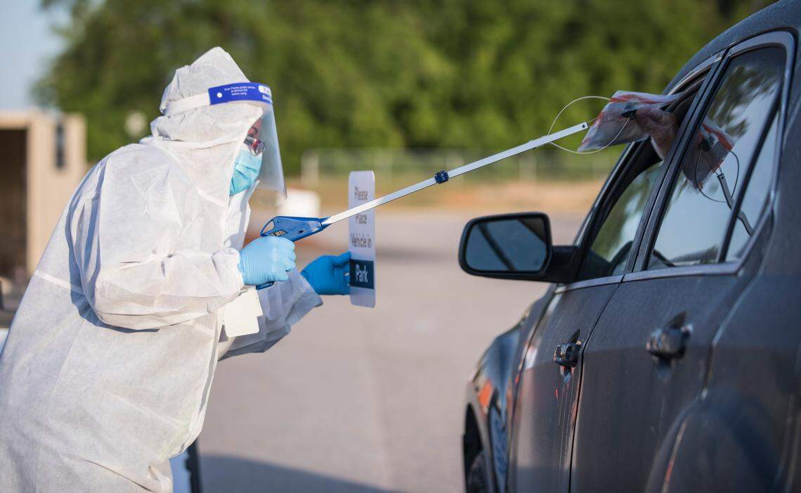 Onyx Flowers, a pharmacy associate with Walmart, safely gives a pre-registered individual a COVID-19 test to be self administered in their car with their window up at the Ramsey Street Walmart parking lot in Fayetteville, N.C. on Friday, May 15, 2020. The tests, which will be processed by eTrueNorth, are now available to people who qualify and pre-register from 7a.m. to 9a.m. on Mondays, Wednesdays and Fridays.
